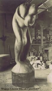 black and white photo of large figurative wood sculpture depicting a passionate embrace of two people. 