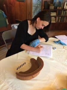 wood model of curved sofa sits on a table with young woman filling out a form.