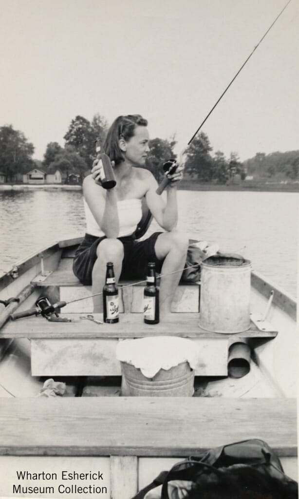 woman seated ina boat, drink beer and fishing on a lake