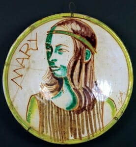 ceramic plate with grena nd brown painting of young girl with headband in three-quarters view.