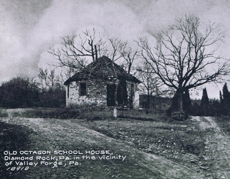 black and white historic photo showing schoolhouse in disrepair with roof shingles missing and walls crumbling.