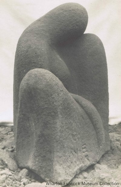 sandstone carving of seated figure simplified to three mounded forms