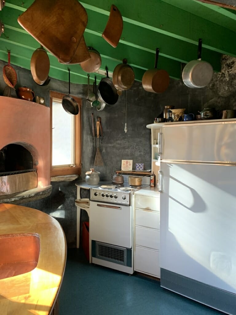 view of kitchen with pots hanging from veiling, counter height fireplace and curved wood counter
