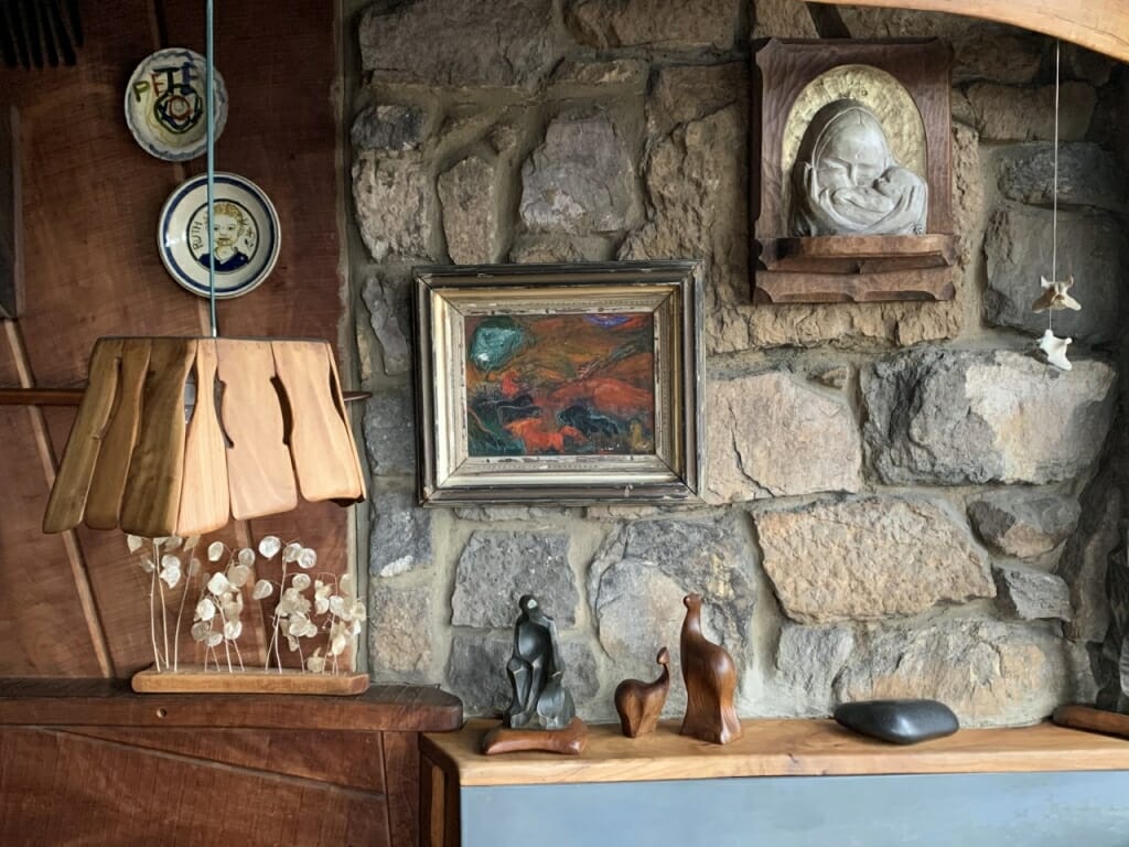 dining room wall, part wood, part stone with ceramic plates, soapstone carving and painting on display