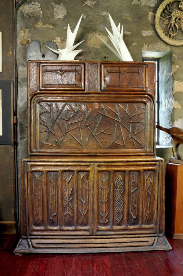 large drop leaf desk with carved surface with designs of trees and bare branches