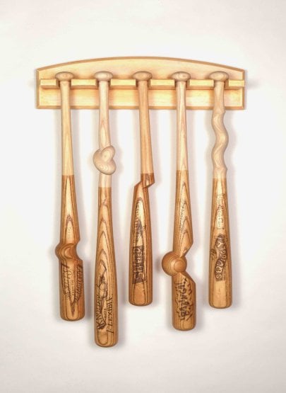 five misshapen wooden baseball bats hang on the wall.