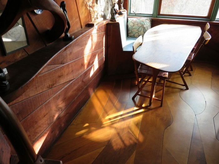 view looking down on wood floor, wall, and table with beams of light from the window pouring in