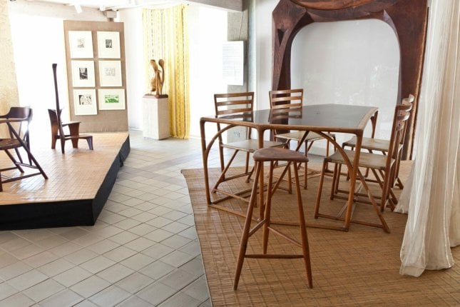 Installation view of gallery displaying tables, chairs and stools by Esherick with fabric dividers and backdrops. A large wood archway stands at the back wall.