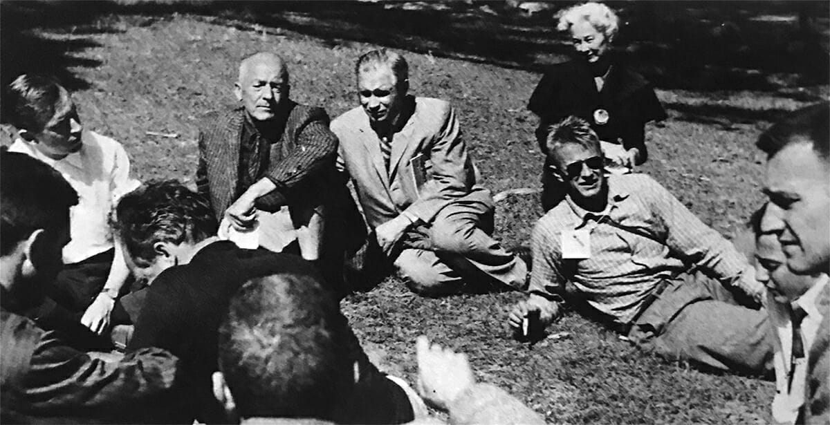 black and white photo of group of people sitting in the grass