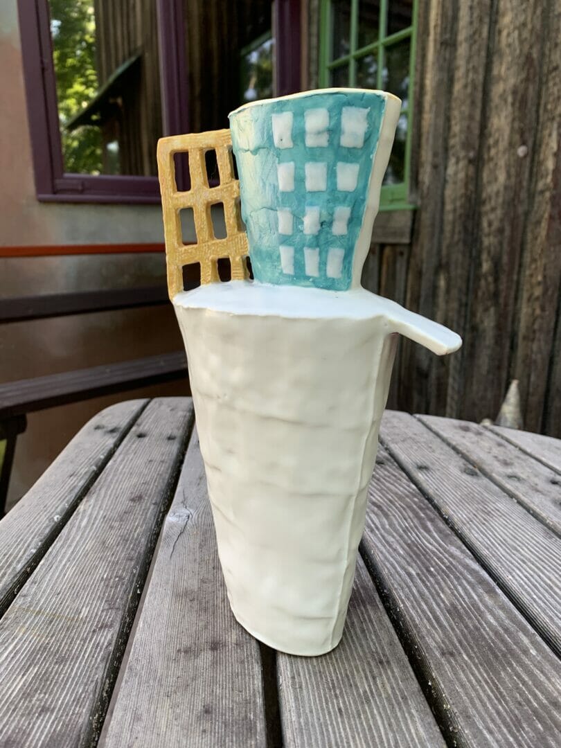 tall and narrow ceramic vase with yellow grid and turquoise top, on Esherick's deck table