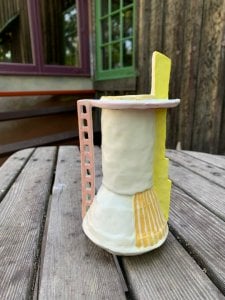 small vase with painted orange lines, tall yellow "chimney" and ladder-like handle