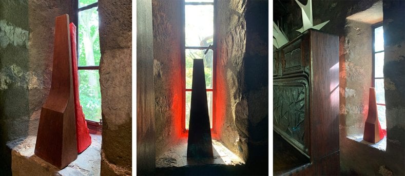 Three views of a deeply recessed window with a pine sculpture with a red sculpture behind it which casts red reflections onto the stone wall.