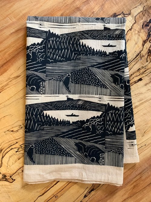 folded beige tea towel with repeating block print pattern