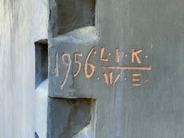 1956 and the initials LIK and WE carved into the side of a blue wall